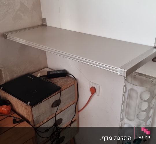 מדף מותקן על קיר מעל שידה עם כבלים חשמליים